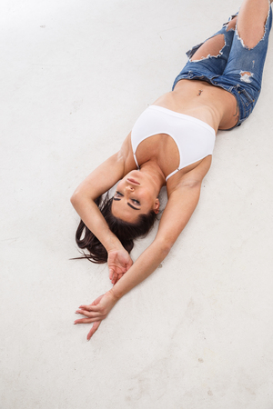 Beautiful blonde girl sexy fitness posing on white background in jeansの写真素材