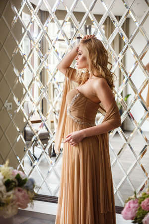 Beautiful girl sexy blonde in dress posing in restaurant, flowersの写真素材