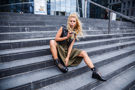 Beautiful blond girl in stylish clothes posing outdoors in the city
