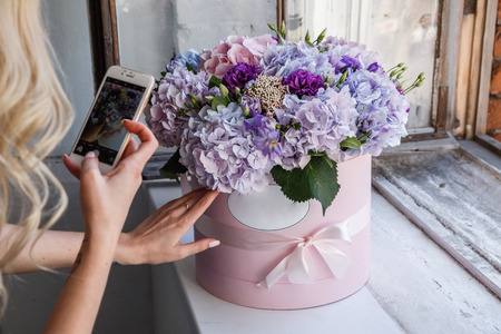 Beautiful girl blonde in dress posing with flowers in bright interiorの写真素材