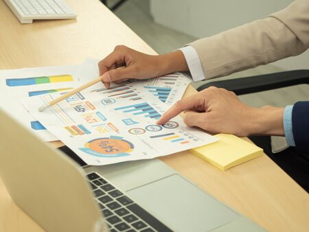 Business persons using a computer laptop, planing charts and discussion with the partner planning sales to meet targets. budget plan concept.の写真素材