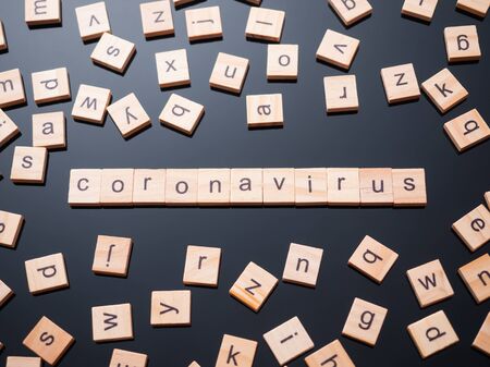 wooden alphabet tiles on the black glass table and words "coronavirus" among the tiles. Wooden  tile, wooden alphabet tiles or wood letter tiles.の写真素材
