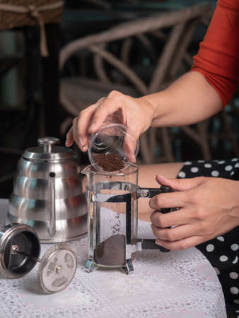 Putting ground coffee into french press pot. Preparing to make coffee with a french press technique.の写真素材