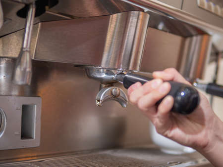 barista putting a portafilter to group head of espresso machine. Barista hand holding portafilter.の写真素材