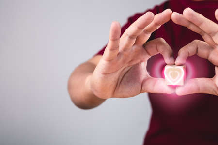 Person shows hands sign of love with heart visual effect. The man with red shirt in medium close up shot. Valentine's concept. Copy space for messages, words and texts.の写真素材