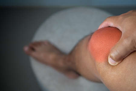 The man holds his pain point of knee joint. The red point shows position of Injury.の写真素材