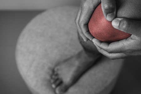The man holds his pain point of knee joint. The red point shows position of Injury. Black and white color.の写真素材