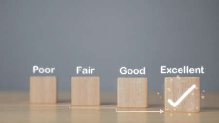 Evaluation and satisfaction concept. On wood blocks, a correct mark shows an excellent job and best service for customer. Copy space on grey background.の写真素材