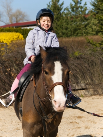 Happy little girl riding on ponny horseの写真素材