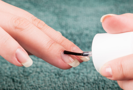 Woman using transparent nailpolish during making manicure herselfの写真素材