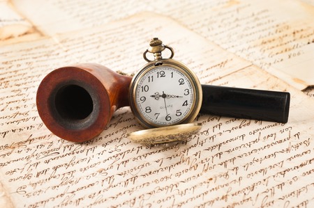 pipe and pocketwatch on letters background