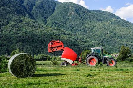 Tractor with round baler in a meadowの写真素材
