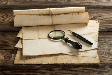 Fountain pen and magnifying glass with old sheets on wood backgroundの写真素材