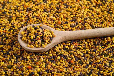 Wooden spoon on bee pollen background