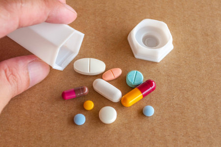 colorful pills, tablets and capsules spilled from a container on backgroundの写真素材