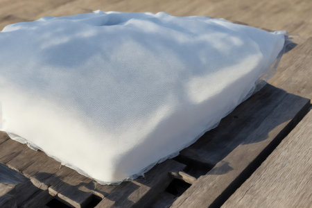 White pillow on the wooden table in the garden. Soft focus.の素材
