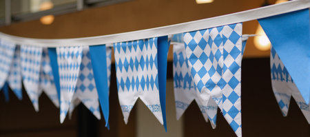 A graphic art illustration showcasing the classic Oktoberfest Garland with triangular flags in the traditional blue-and-white checkered pattern representing Bavarias identityの素材