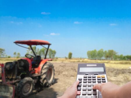 Investment cost concept by calculator and the blur farm and tractor in backgroundの写真素材