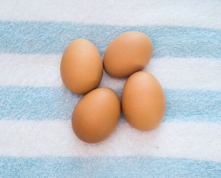 Fresh three eggs put on the white-blue cotton
