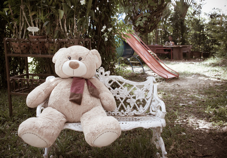 Alone thinking concept by bear doll sit on the seat in gardenの写真素材
