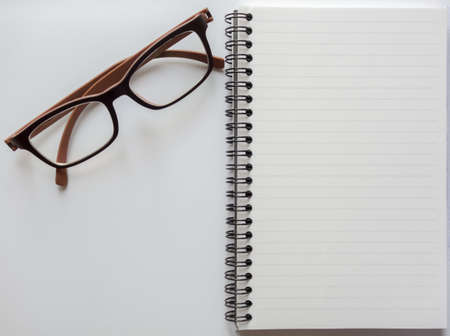 Top view of blank notebook with glasses on white background with space