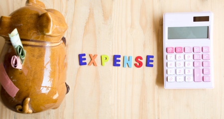 Expense word with piggy bank and calculator on wooden backgroundの写真素材