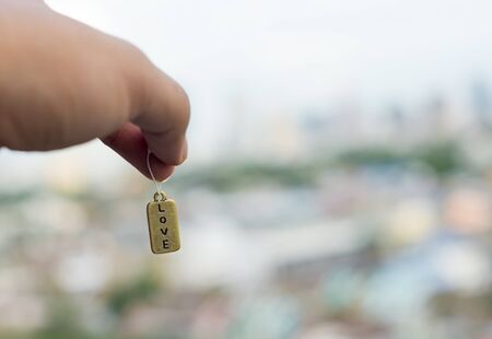 The love tag hanged by hand with city in backgroundの写真素材