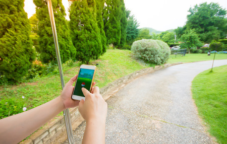 BANGKOK, THAILAND - AUG 19, 2016: The hit augmented reality smartphone app "Pokemon GO" shows a Pokemon encounter overlain on a garden park in the real world.のeditorial素材
