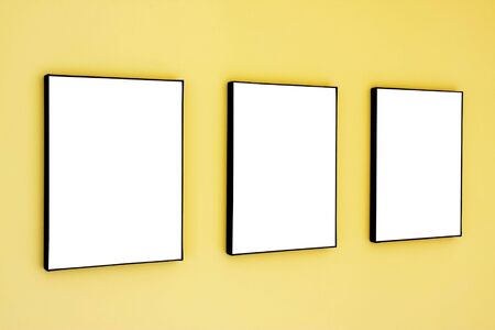 Three blank frames on a yellow wall.の写真素材