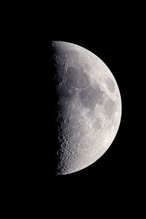First quarter moon, photographed at the prime focus of a C5 telescope, with craters and surface details visible.の写真素材