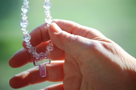hand holding a glass cross with pink beadsの写真素材