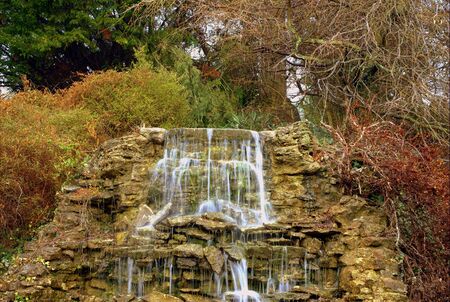 secluded waterfall  cascading over rocks in dense foliage