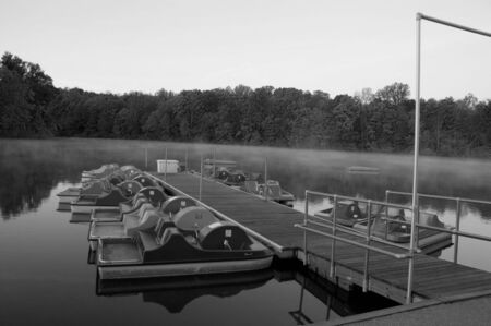 paddle boats docked  on misty lake black and whiteの写真素材