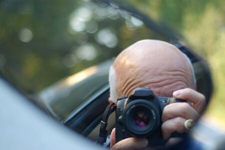 man taking pictures of storm damage from car window closeup