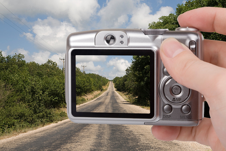 Digital camera in a hand. Photo on screen and background is my own shotの写真素材