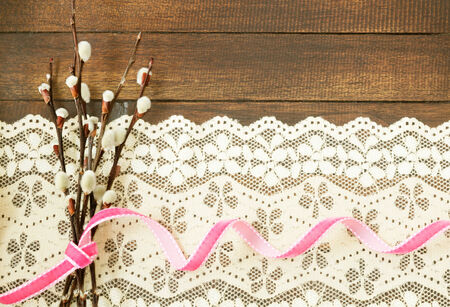 Branches of willow with pink ribbon on wooden backgroundの写真素材