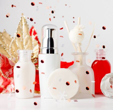 spa cosmetic bottles with fallen confetti on grey background. Red and white. Christmas gift, Body care, skin treatment concept. Text spaceの写真素材