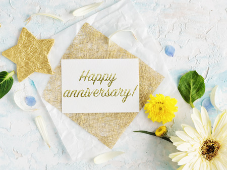 bright summer flowers mock up with craft paper and gold stars. Greeting card. happy anniversary letteringの写真素材