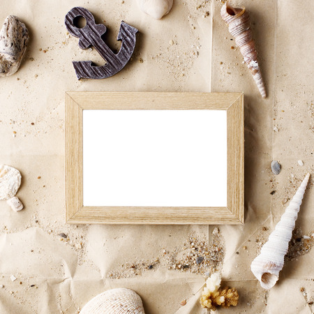 vintage wooden photo frame on craft paper with sand and sea shells mock up. Travel, summer concept. Text spaceの写真素材