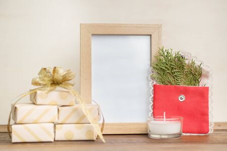 gifts wrapped in craft paper with photo frame and christmas tree branch on wooden table on bright...