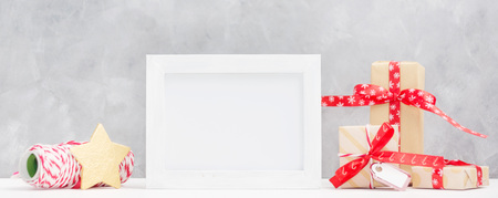 Bright christmas mock up with photo frame: festive gift boxes, wrapping thread and gold star. New year concept. Text space. Greeting card templateの写真素材
