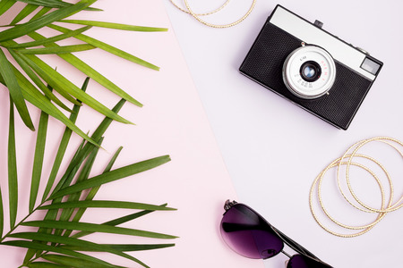 Boho style mock up: palm leaves, vintage camera, golden bangles and sunglasses on colorful pink and purple background. Travel concept. Trendy colors. Text spaceの写真素材