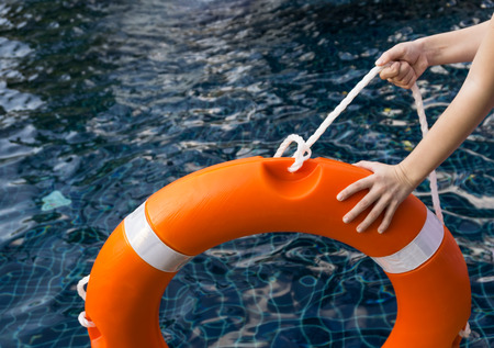 Child's hands holding lifebuoy against dangerous dark water in swimming pool. Safety, parents fears...