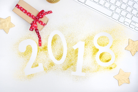 Luxury glowing numbers 2018 made from gold shiny glitter on white table with keyboard and christmas decoration. Red, white, gold. New year concept. Text spaceの写真素材
