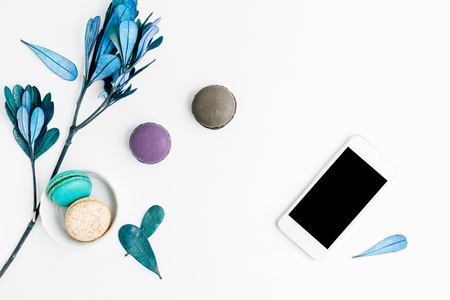 Top view flat lay colorful macarons with  cell phone and blue leaves. Creative dessert concept, text spaceの写真素材