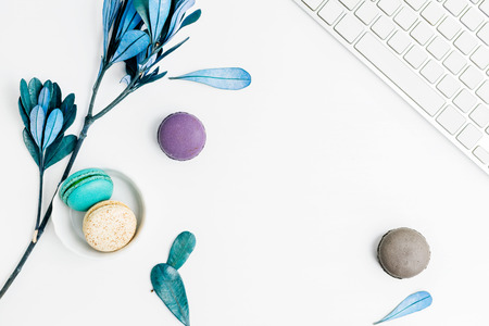 Top view flat lay colorful macarons with keyboard and blue leaves. Creative dessert conceptの写真素材