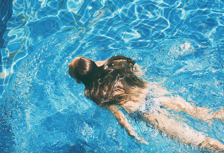 preteen girl in bikini enjoys swimming in the pool. Childhood, vacation, travel concept. Healthy lifestyleの写真素材