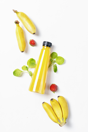 top view flat lay yellow bottle of juice with spinach, banana and strawberries on white background. Healthy lifestyle, vegetarian food concept. Detoxの写真素材