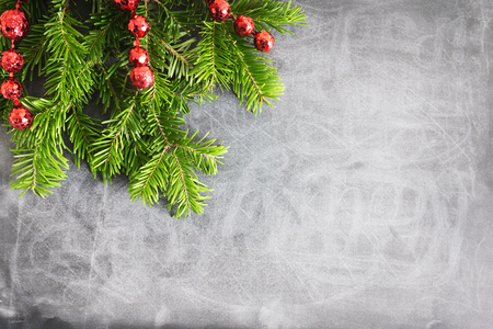 Top view flat lay natural Christmas tree branches with red toys, bow and glass deer corner frame on chalkboard background. New year decor concept. Text spaceの写真素材