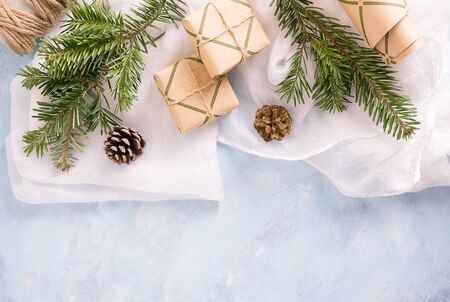 flat lay top view christmas tree branches with toys, fir-cones and gifts in craft paper on blue background. New year holiday concepr. Text spaceの写真素材